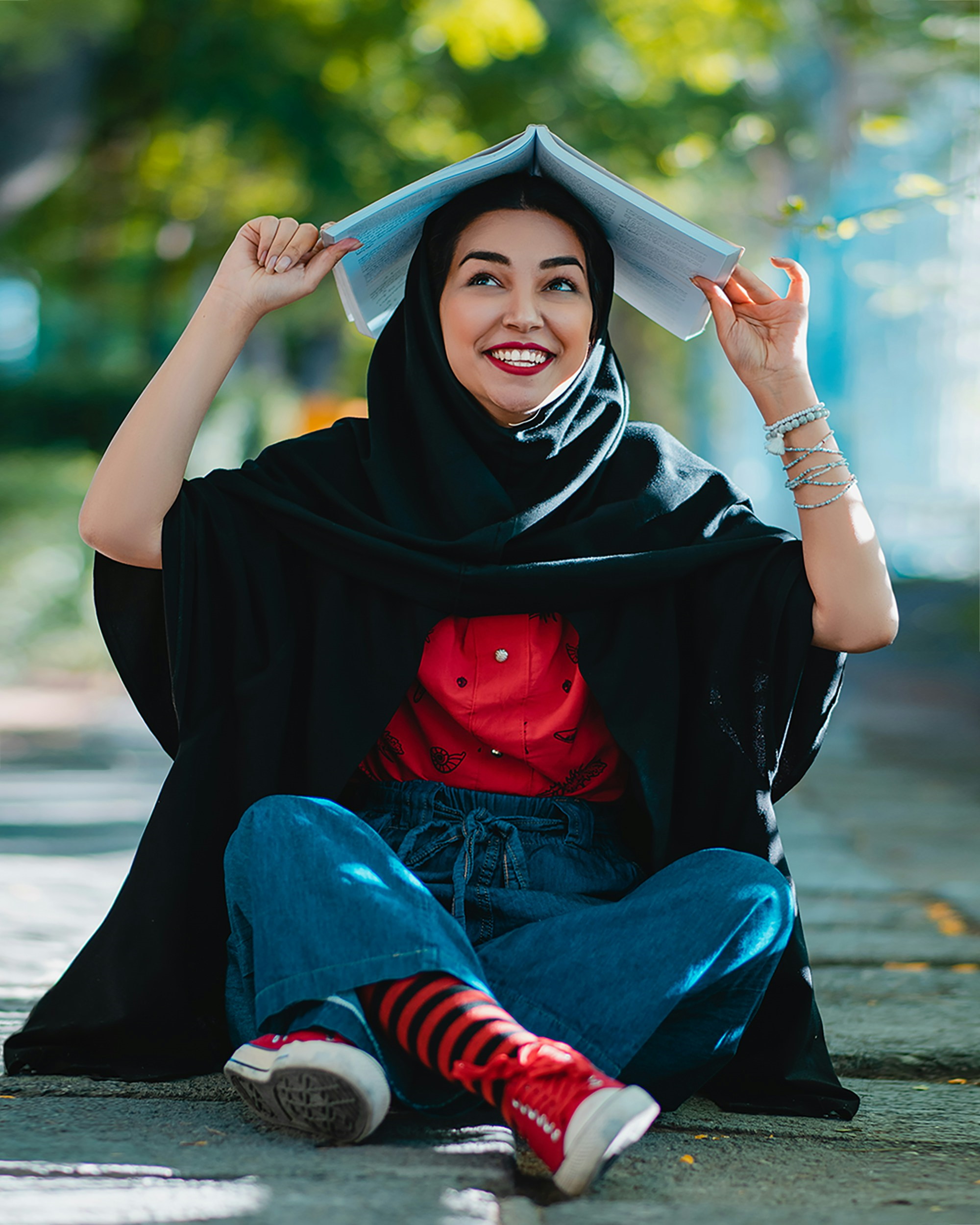 Smiling female student with open book on top of her head